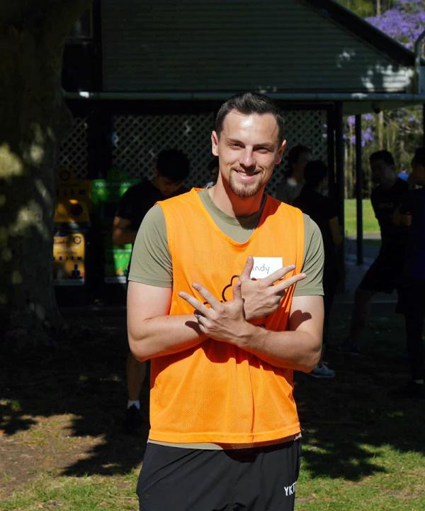 Image of 20 something man wearing orange volunteer bib in park