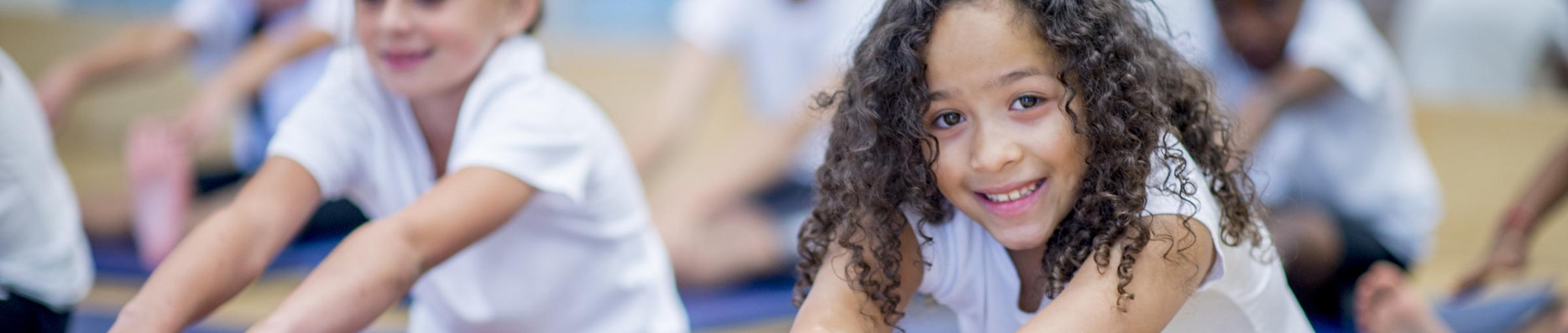 Image of girl with dark curly hair doing a seated stretch