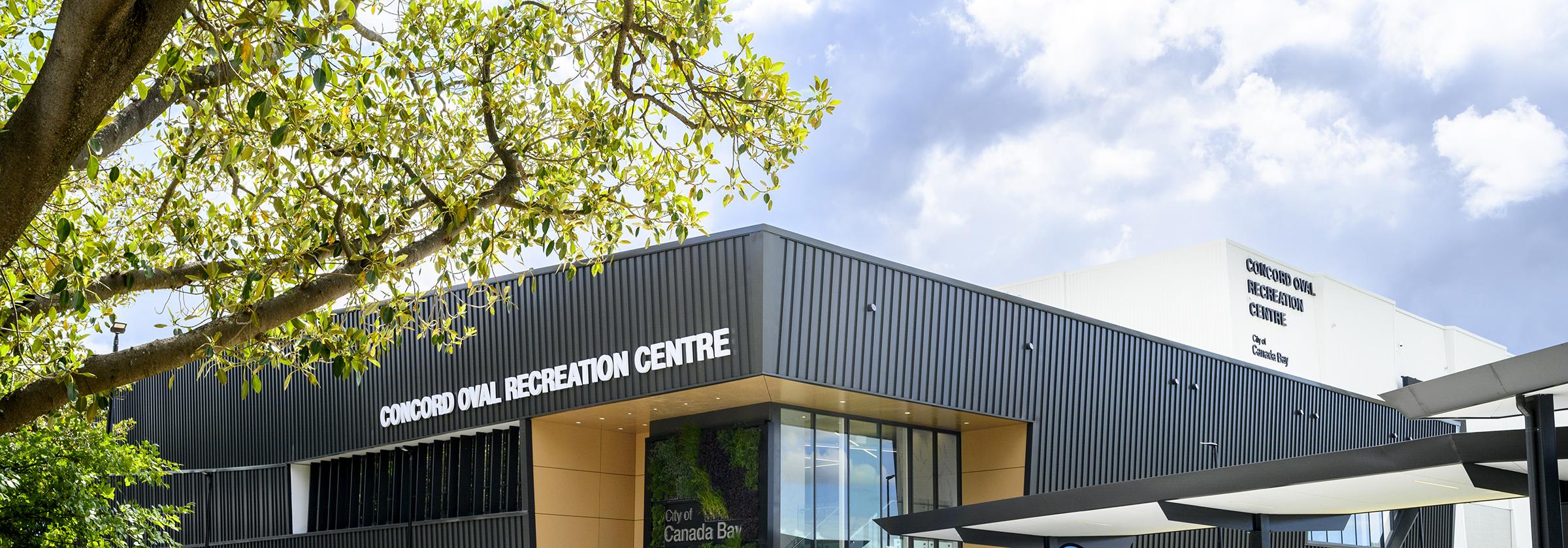 Building with text that says Concord Oval Recreation Centre with trees in foreground