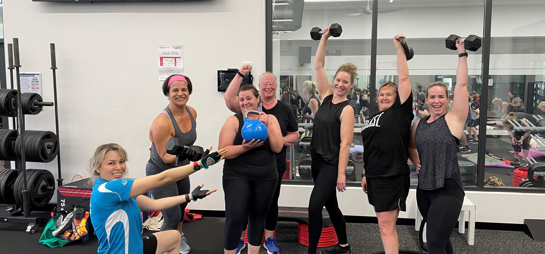 women in gym class holding dumbbells