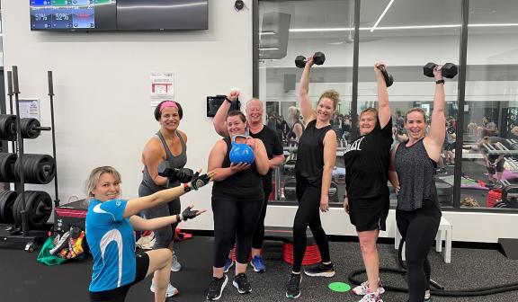 women in gym class holding dumbbells