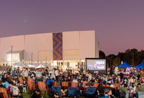 The sun sets over a large crowd infront of the Concord Oval Recreation Centre